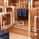 HVAC installation showcasing an intricate network of white pipes and blue control boxes, highlighting Atlantic Heating & Air Conditioning's expertise in heating and cooling systems.