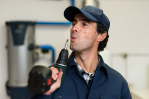 Man in work attire holding a power drill, representing HVAC maintenance and repair services for Atlantic Heating & Air Conditioning.