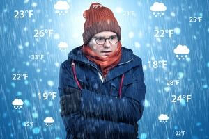 Person bundled in winter clothing, shivering in cold weather with various temperature readings around, illustrating the importance of optimal thermostat settings during cold months.