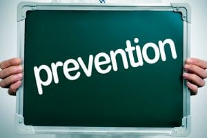 Hands holding a chalkboard displaying the word "prevention," emphasizing the importance of preventing HVAC leaks through regular maintenance and inspections.