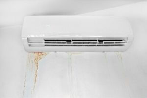 Leaking HVAC unit with water stains on the wall, indicating potential refrigerant or water leaks, relevant to HVAC maintenance and leak prevention.