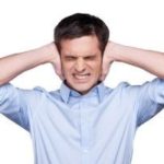 Young man in a light blue shirt covering his ears, representing discomfort from loud boiler noises.