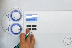 Boiler thermostat control panel with digital display and adjustment knobs, illustrating boiler maintenance related to humming noises in plumbing systems.