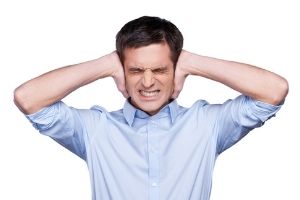 Man covering his ears in distress, illustrating the unsettling sounds from a boiler system during the heating season.