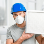 Male worker in blue hard hat holding an air filter, highlighting HVAC maintenance for improved indoor air quality.