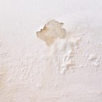 Damaged wall with light brown stains and textured surface, indicating neglect in HVAC-maintained home.