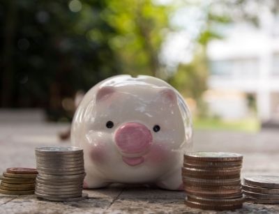 Piggy bank surrounded by stacks of coins, symbolizing savings and financial efficiency related to heat pump investment for homeowners.