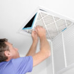 Repairman servicing a ceiling vent and air filter for better HVAC performance at Atlantic Heating & Air Conditioning.