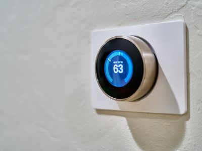 Programmable thermostat displaying a temperature of 63 degrees Fahrenheit, illustrating energy-efficient cooling solutions for homeowners.