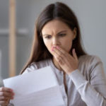 Woman with a concerned expression holding paper, representing HVAC service concerns from Atlantic Heating & Air Conditioning.
