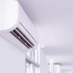 Modern air conditioning unit mounted on wall in bright indoor setting with clean design and visible vents.