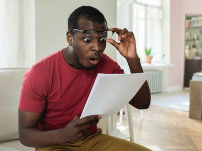 Surprised man reading a document, illustrating the shock of increased energy bills due to an old furnace's inefficiency.