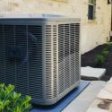 Outdoor central air conditioning condenser unit installed beside a residential home.