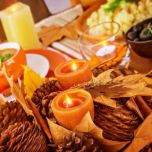 Autumn-themed table setting with candles, pinecones, and decorative leaves, evoking seasonal warmth and preparation for winter home maintenance.