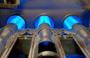 Close-up of furnace burners with blue flames, illustrating the heating process for efficient HVAC operation, relevant to winter furnace maintenance and repair services.
