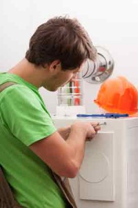HVAC technician repairing a furnace, wearing a green shirt, with tools and an orange hard hat nearby, emphasizing professional furnace maintenance services in Boston.