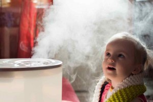 Child looking up at a humidifier emitting steam, demonstrating the benefits of humidifiers for improving indoor air quality and comfort during fall and winter.