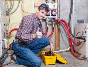 HVAC technician giving a thumbs up while working on a furnace maintenance service, showcasing expertise in preparing heating systems for winter.