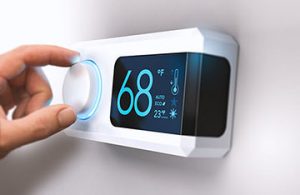 Hand adjusting a programmable thermostat displaying 68°F, illustrating energy-efficient temperature control for winter heating.